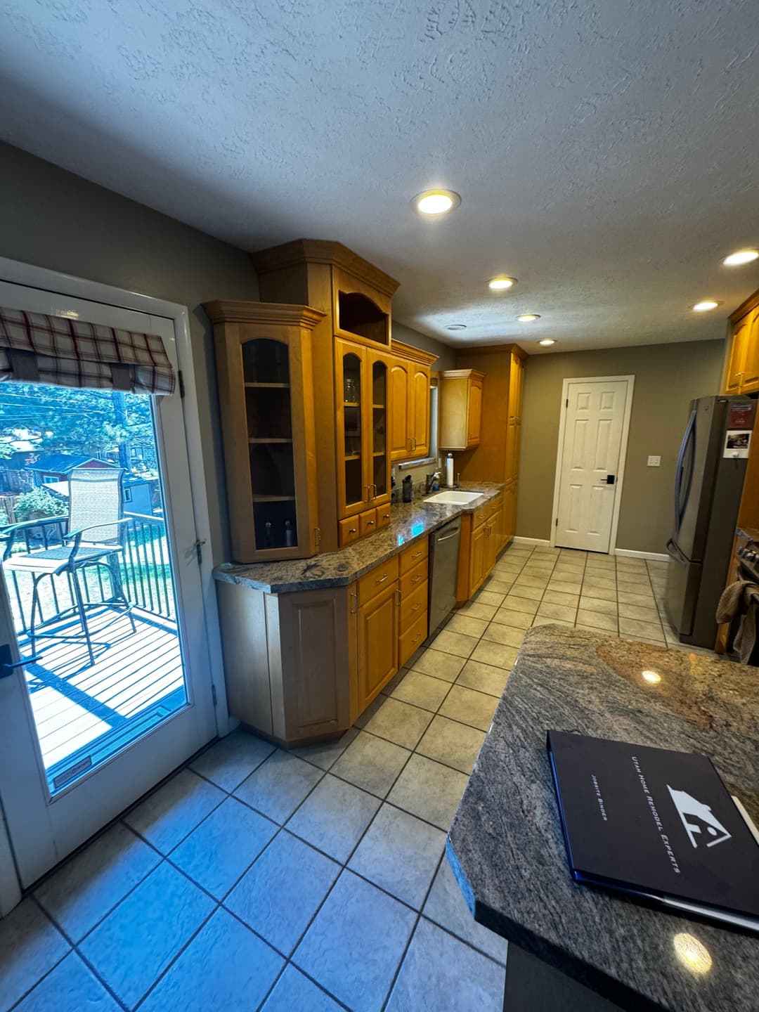 Spacious kitchen with wooden cabinetry, granite countertops, and natural light from the patio door.