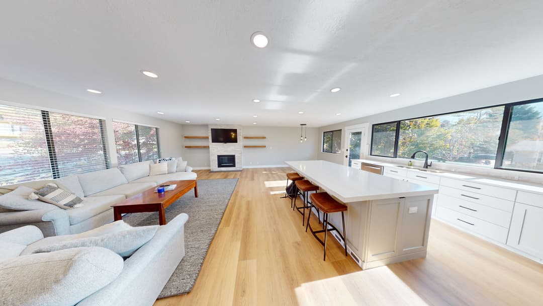 Modern open-concept living room and kitchen with natural light and stylish decor.
