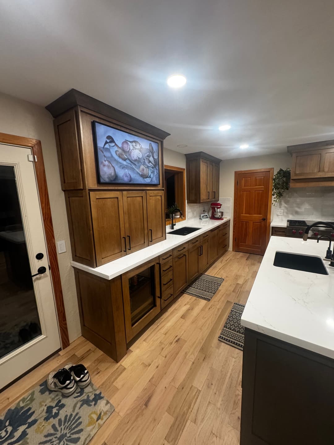 Modern kitchen with wooden cabinets, marble countertop, and a wall-mounted art piece.