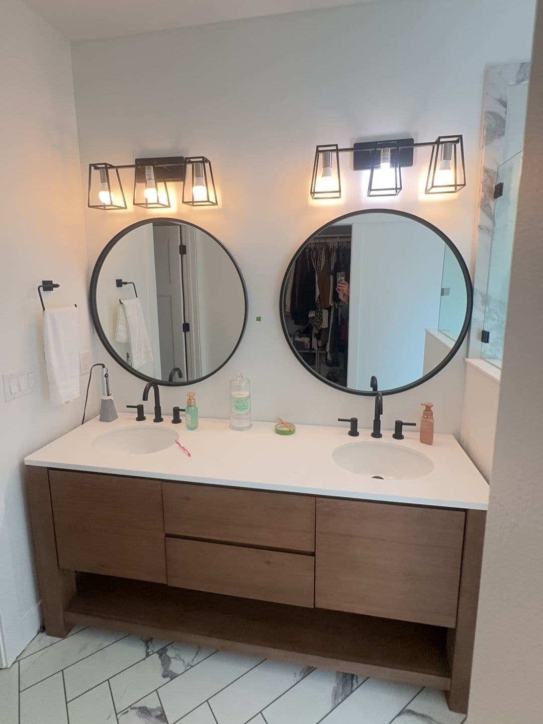 Modern bathroom with dual circular mirrors, stylish lighting, and wooden vanity.
