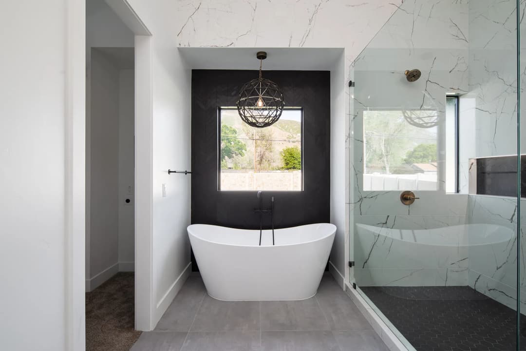 Modern bathroom featuring a freestanding tub, glass shower, and elegant lighting fixture.