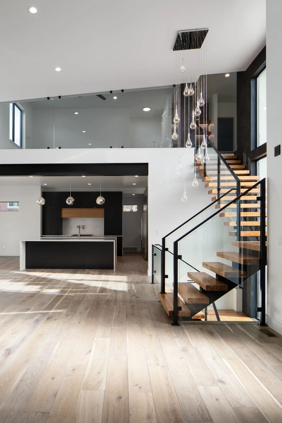 Modern open-concept living space with minimalist design, sleek staircase, and stylish lighting.