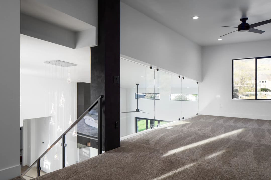 Modern interior with open space, glass railing, and stylish lighting fixtures.
