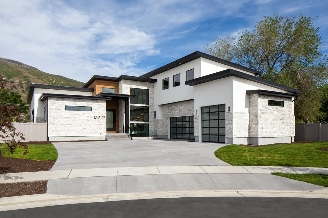 Modern two-story home with stone exterior, large windows, and landscaped yard.