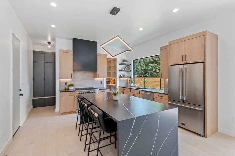 Modern kitchen with sleek cabinetry, a large island, and stylish lighting fixtures.