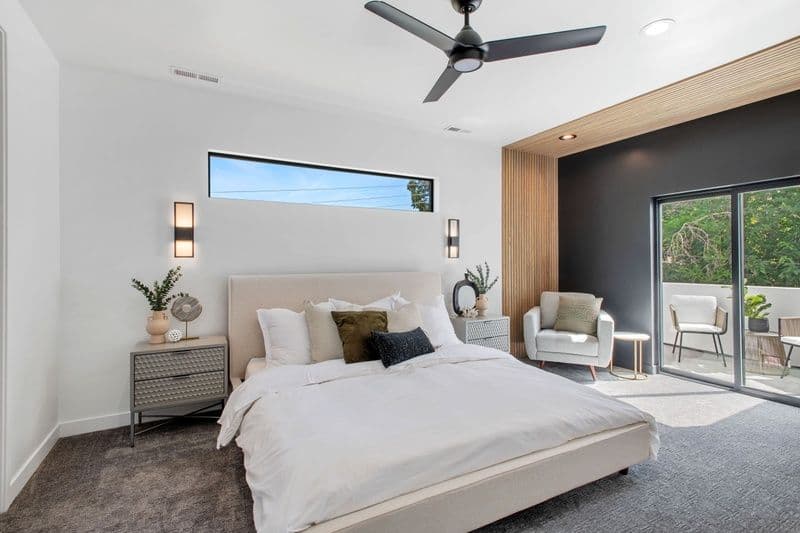 Modern bedroom with minimalist decor, large window, stylish bedding, and balcony access.