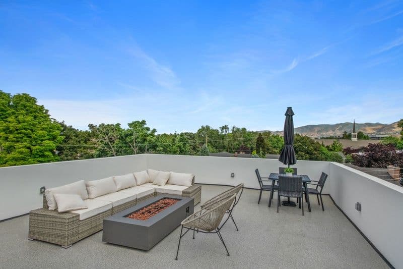 Rooftop terrace with seating, fire pit, dining table, and scenic mountain views.