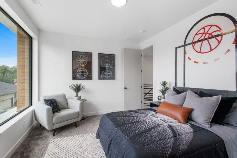 Modern bedroom featuring basketball-themed decor, cozy seating, and large windows.