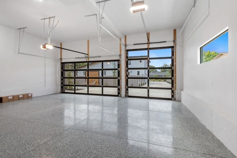 Spacious modern garage with glass doors, polished concrete floor, and natural lighting.