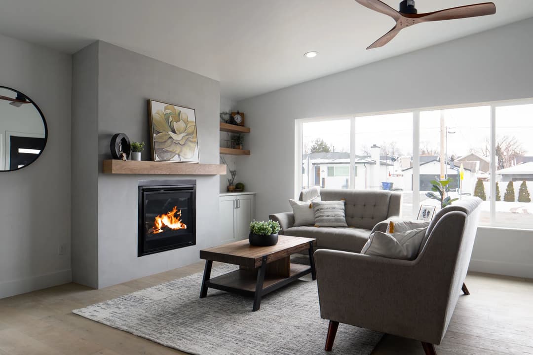 Modern living room with a fireplace, large window, and stylish furniture. Bright and inviting space.