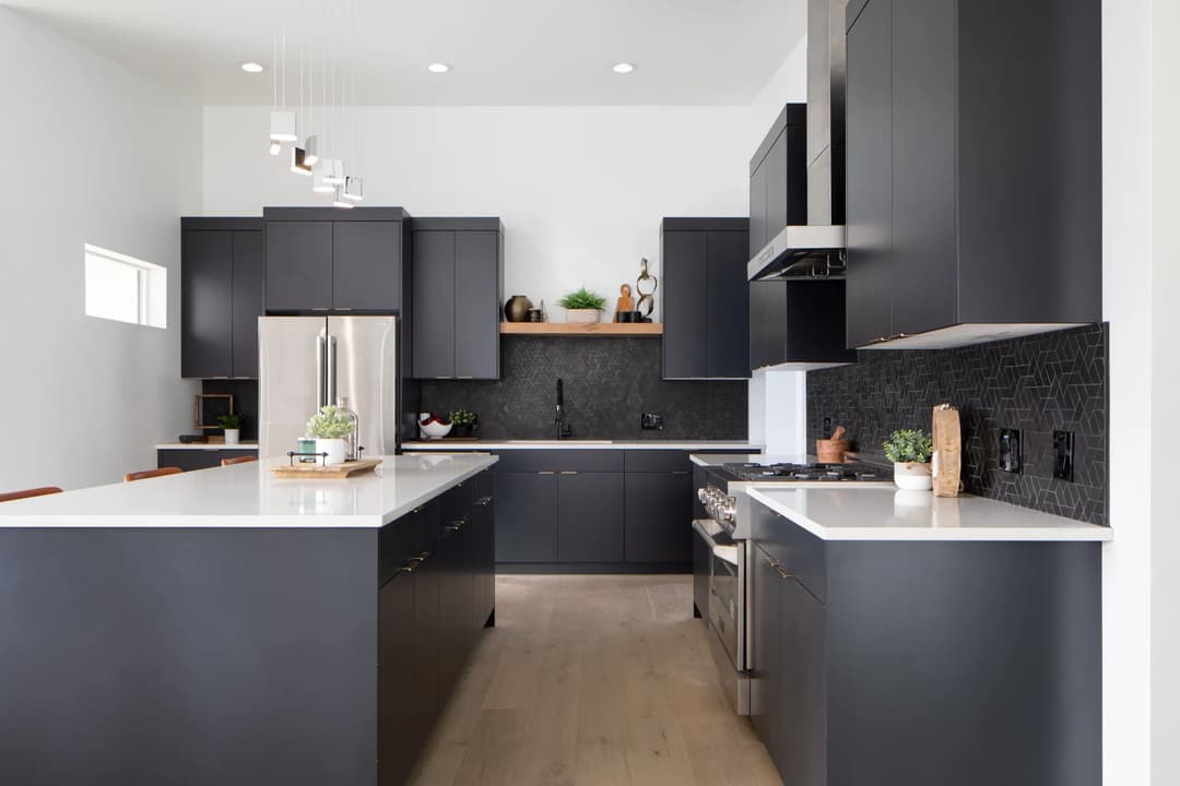 Modern kitchen with gray cabinetry, stainless steel appliances, and white countertops.