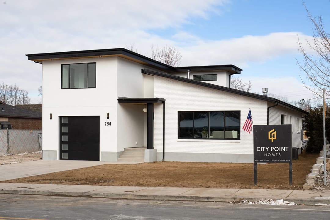 Modern home exterior with large windows, American flag, and City Point Homes sign.