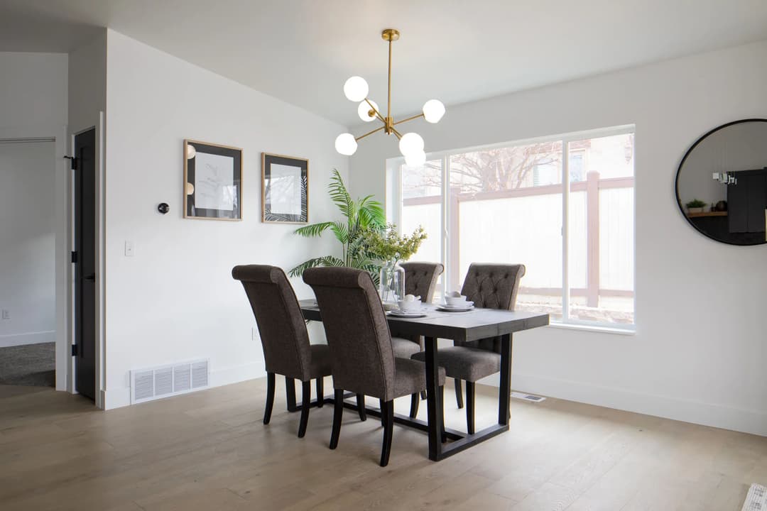 Modern dining room with a stylish table, elegant chairs, and a bright window view.