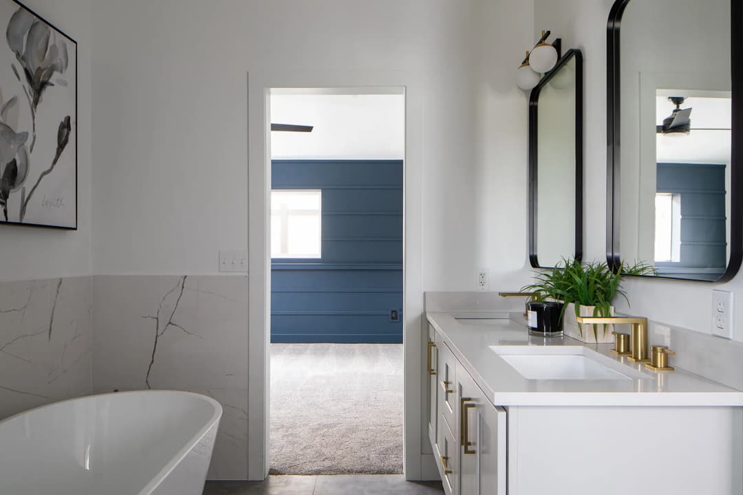 Modern bathroom design featuring a freestanding tub, dual mirrors, and a blue accent wall.