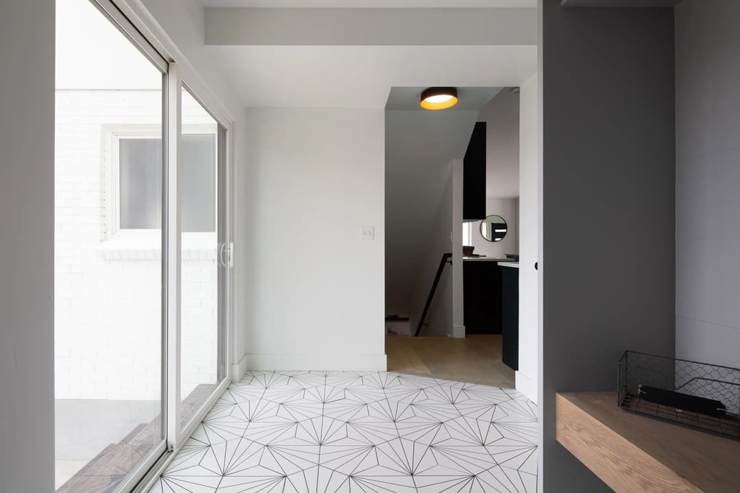 Modern minimalist interior featuring geometric patterned floor and sliding glass door.