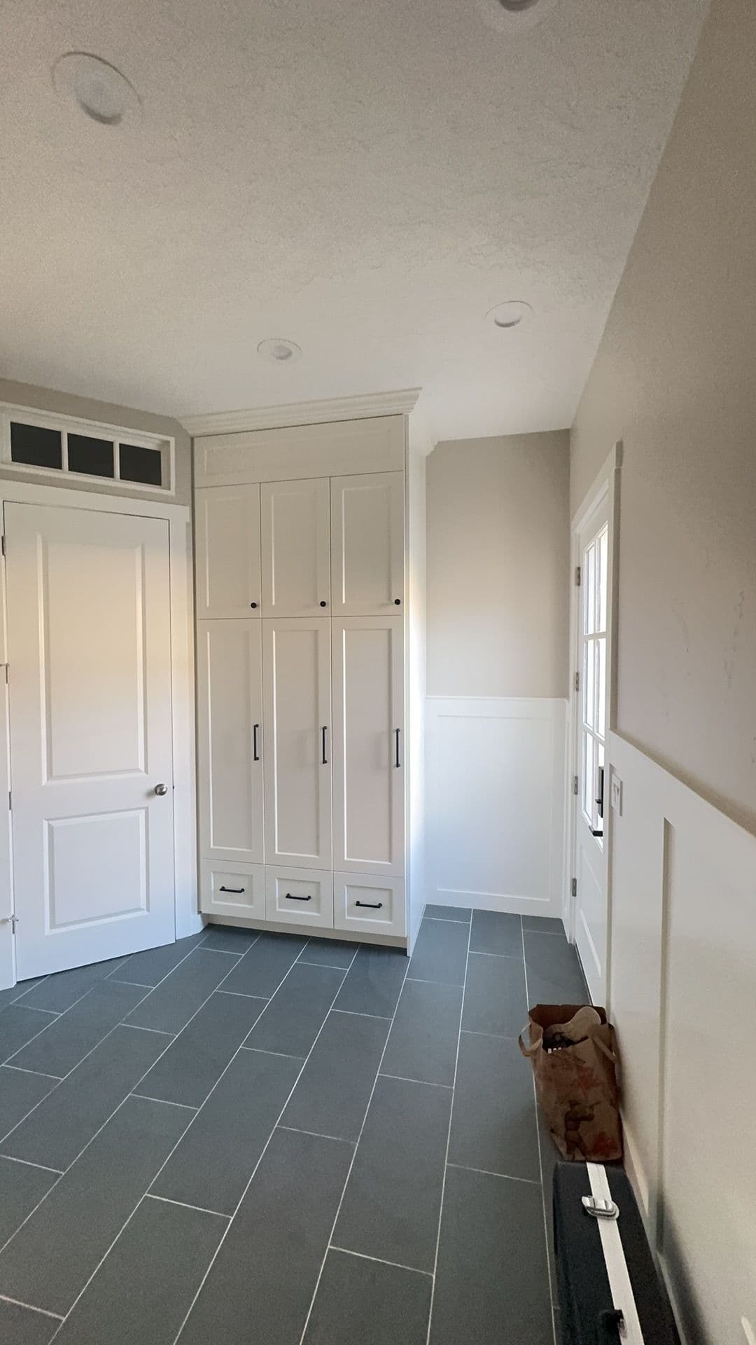 Modern entryway with built-in cabinetry, gray tile flooring, and neutral wall colors.