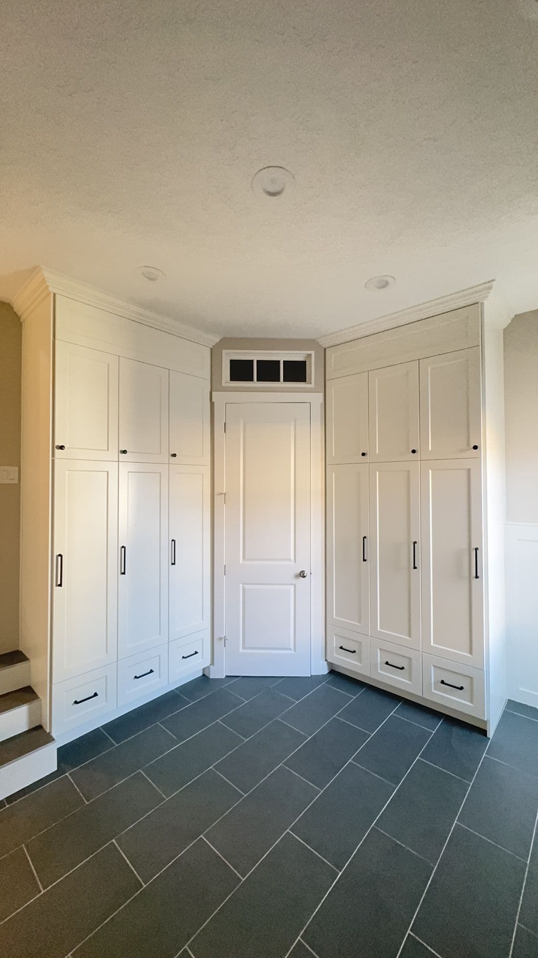Modern entryway with white cabinetry, built-in storage, and a stylish gray tile floor.